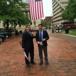Hampden District Attorney Anthony Gulluni and Springfield Mayor Domenic Sarno take a photo underneath an American flag.