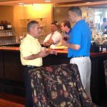 Two people talking with one another next to a bar at an event.