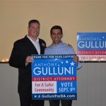 Hampden District Attorney Anthony Gulluni and another person smile and hold a campaign sign.