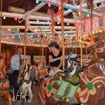 Three people ride a carousel.