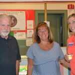 Three people smile and pose for a photo.