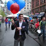Hampden District Attorney Anthony Gulluni walking down a street, holding balloons.