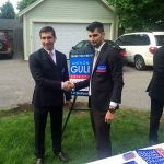 Hampden District Attorney Anthony Gulluni shakes hands with a person in a suit at an outdoor campaign event.