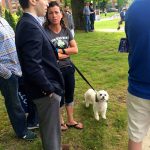 Hampden District Attorney Anthony Gulluni talks to a woman who is holding a white dog's leash.