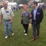 Hampden District Attorney Anthony Gulluni walks and talks to two people at a fair.