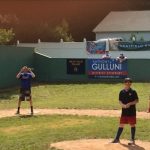 Two people stand on a baseball field.