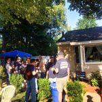 A group of people mingle outside of a home.