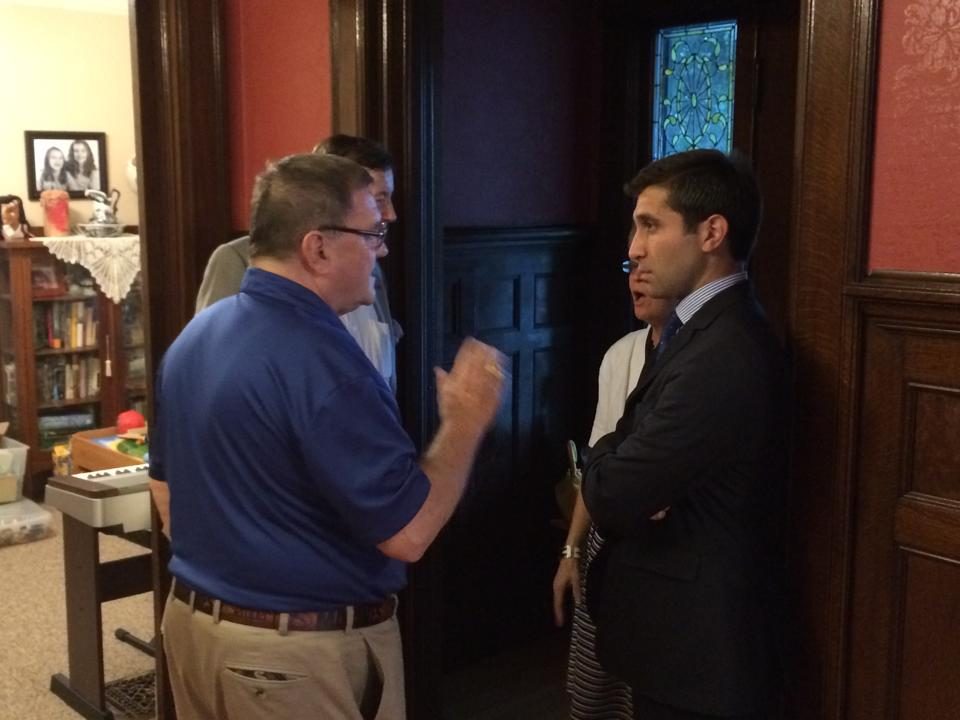 Hampden District Attorney Anthony Gulluni stands and talks to three other people.