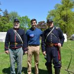 Hampden District Attorney Anthony Gulluni takes a photo with two people dressed in 19th century military fatigues.