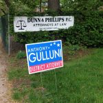 A lawn sign for Hampden District Attorney Anthony Gulluni next to a sign for Dunn & Phillips P.C.
