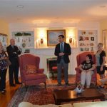 Hampden District Attorney Anthony Gulluni talks in a living room as others listen.