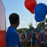 A person holding balloons at an outdoor event.