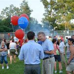 Hampden District Attorney Anthony Gulluni holds balloons and talks to a person at an outside event.