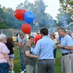 Hampden District Attorney Anthony Gulluni talks to people while holding balloons at an outdoor event.