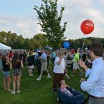 Hampden District Attorney Anthony Gulluni carries a balloon while walking through an outdoor event.