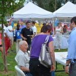 Hampden District Attorney Anthony Gulluni talks to a seated person at an outdoor event.