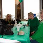 Four women sit at a table adorned with a green tablecloth.