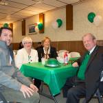 Four people sitting at a table with a green tablecloth.