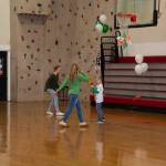 Three kids play at an event held in a gymnasium.