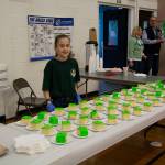 A child volunteering at a dessert table.