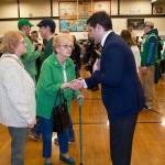Hampden District Attorney Anthony Gulluni shakes hands with an elderly woman as another person looks on.