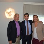 Hampden District Attorney Anthony Gulluni smiles and poses with two people.