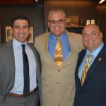 Hampden District Attorney Anthony Gulluni smiles for a photo with two men.