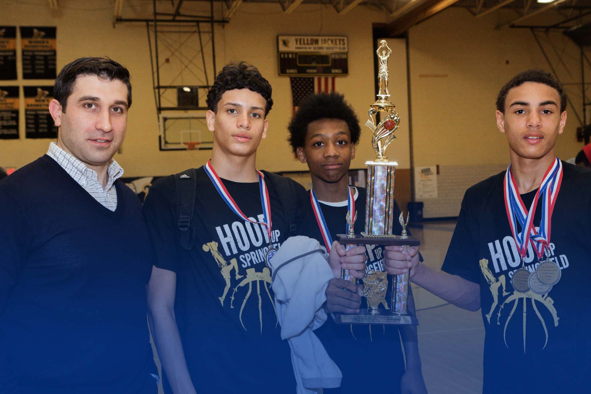 Hampden District Attorney Anthony Gulluni poses for a photo with three people holding a basketball trophy.